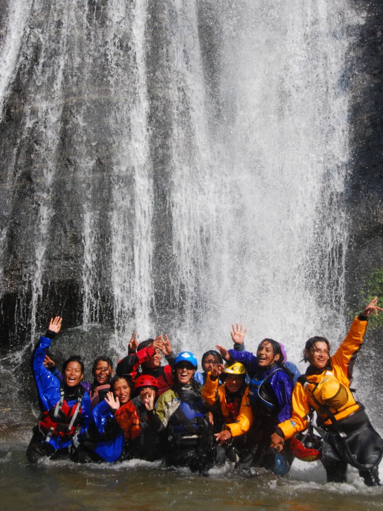 Glada paddeltjejer i ett vattenfall