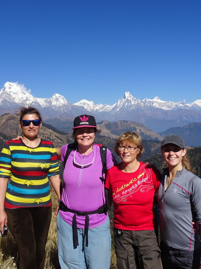 Kvinnlig nepalesisk guide med svenska tjejer med snötäckta berg bakom sig