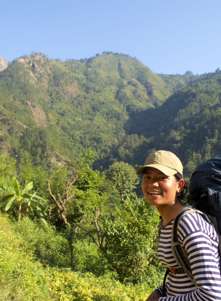 Kamala Magar, en kvinnlig vandringsguide med gröna berg i bakgrunden