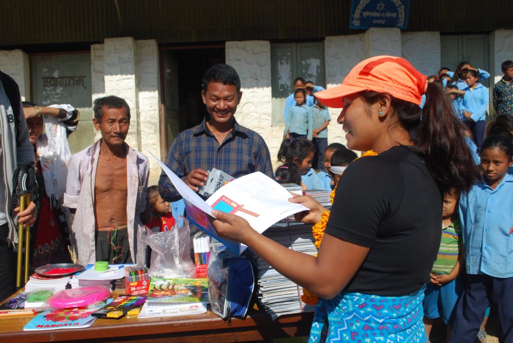 Kvinnlig guide delar ut böcker vid en skola i Nepal