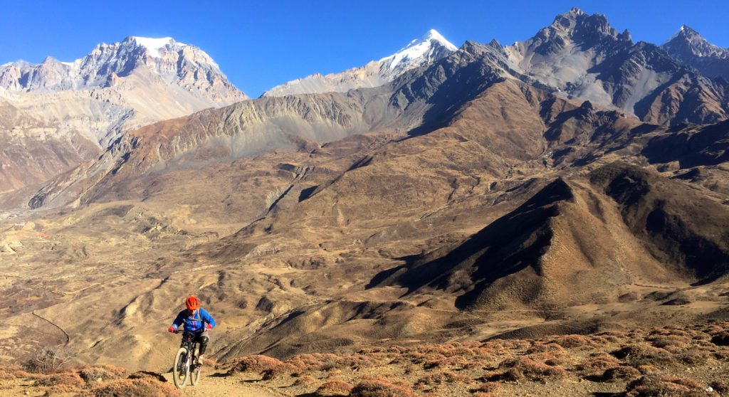 MTB Nepal, en mountainbike-cyklist kommer nerför en stig i ett spektakulärt bergslandskap