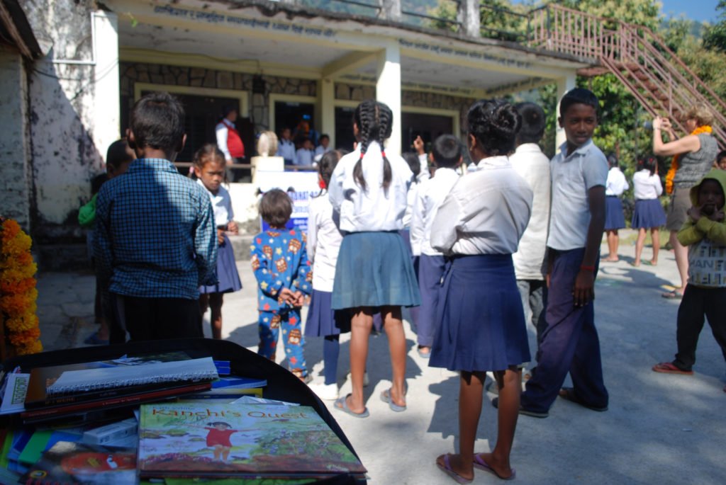 Tjejresa Nepal, skolbarn framför en skolbyggnad samt skolböcker i en väska